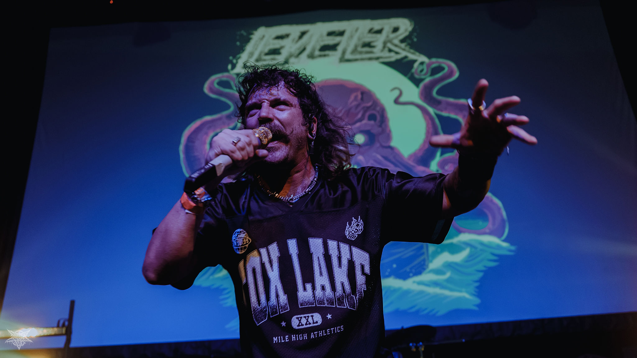 Leveler vocalist reaching into the crowd under blue and purple stage lighting